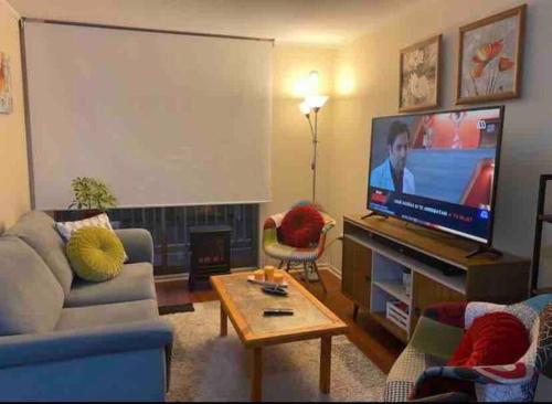 sala de estar con TV de pantalla plana grande en Bonito y acogedor departamento en Los Ángeles