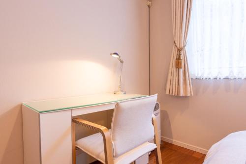 a desk with a lamp and a chair in a room at Noёl HAKONE GENSEN in Hakone