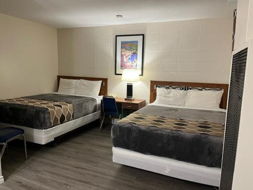 pokój hotelowy z 2 łóżkami i stołem z lampką w obiekcie West Castle Motel w mieście Pincher Creek