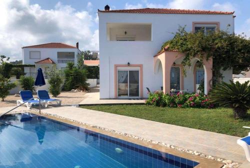 a villa with a swimming pool in front of a house at Royal St.Georges in Fánai