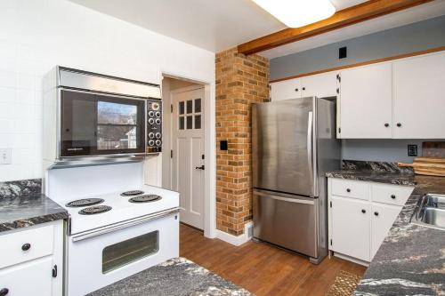 La cuisine est équipée de placards blancs et d'un réfrigérateur en acier inoxydable. dans l'établissement NEW Charming Home in the Heart of North Fargo, à Fargo
