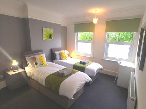 two beds in a small room with two windows at Amazing 2 bed London apartment in London