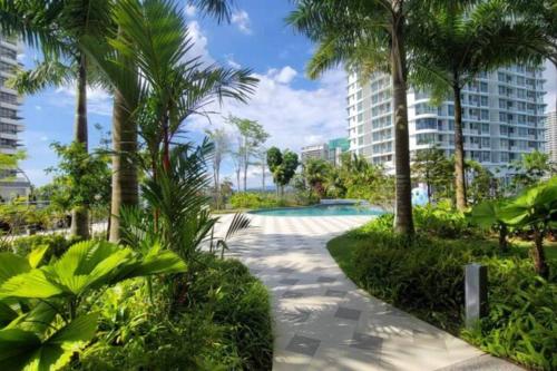 a walkway with palm trees and a swimming pool at Macrolink Medini Legoland by Stayrene in Kangkar Pendas