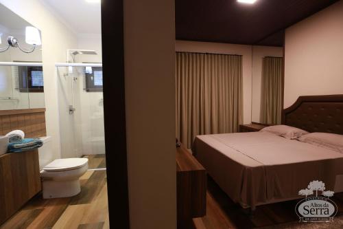 a bedroom with a bed and a bathroom with a toilet at Casa Holidays - Altos da Serra Catarinense in Bom Jardim da Serra