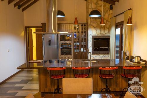 a kitchen with a bar with red stools at Casa Holidays - Altos da Serra Catarinense in Bom Jardim da Serra