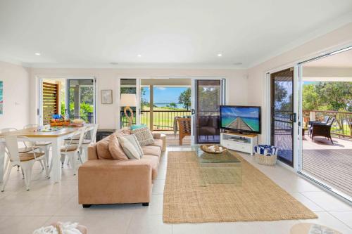 a living room with a couch and a tv and a table at Allure By The Sea in Bonny Hills