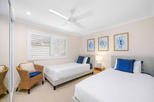 a bedroom with two beds and a chair at Allure By The Sea in Bonny Hills