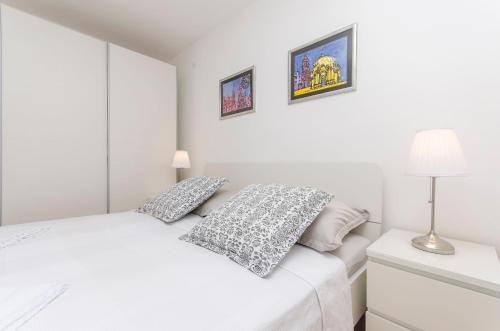 a white bedroom with a white bed with two pillows at Apartment Oblutak in Brodarica