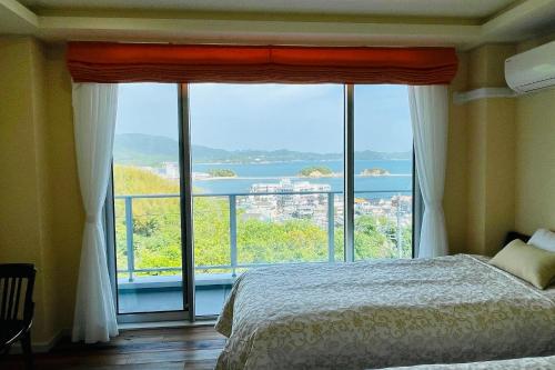 a bedroom with a large window with a view of the water at La Krasse Angelroad WEST in Tonosho