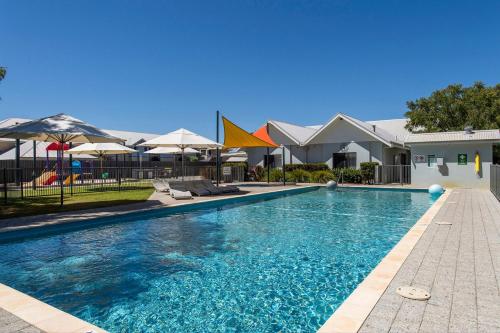 a swimming pool with blue water and umbrellas at Tides at 65 Cape View Resort in Broadwater