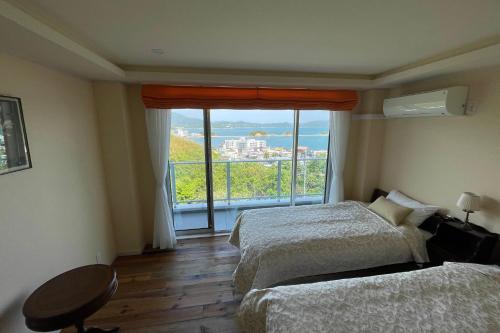 a hotel room with two beds and a large window at La Krasse Angelroad WEST in Tonosho