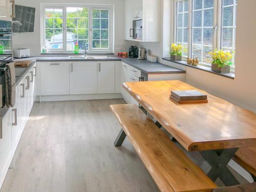 a kitchen with white cabinets and a wooden table at Beech House in Sydenham Damerel