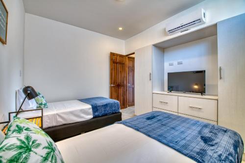 塔瑪琳的住宿－Muna Tamarindo，一间卧室配有两张床和一台平面电视
