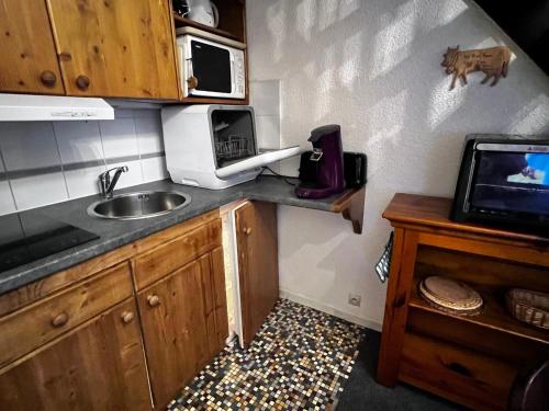 une petite cuisine avec un évier et un micro-ondes dans l'établissement Studio lumineux avec mezzanine, balcon, casier à skis et parking à 5 min du centre de Morzine. - FR-1-524-87, à Morzine