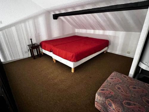 une chambre avec un lit avec une couverture rouge dans l'établissement Studio lumineux avec mezzanine, balcon, casier à skis et parking à 5 min du centre de Morzine. - FR-1-524-87, à Morzine
