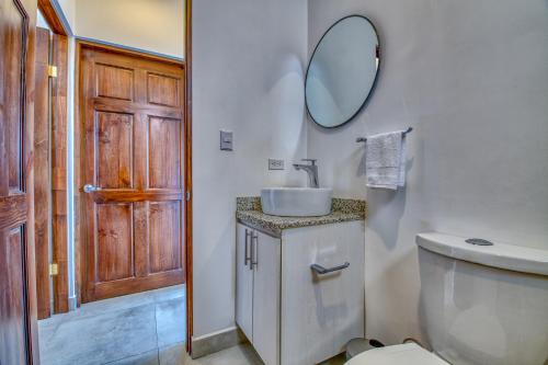 a bathroom with a sink and a toilet and a mirror at Muna Tamarindo in Tamarindo