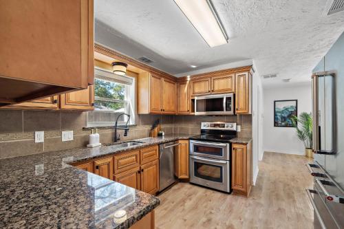 a kitchen with wooden cabinets and stainless steel appliances at The Pines I Sleeps 12 I Private Pool I Patio & BBQ in Conroe