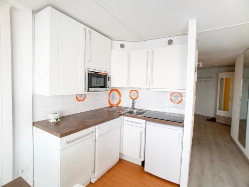 une petite cuisine avec des armoires blanches et un évier dans l'établissement Proche commerces et pistes · Appartement lumineux avec balcon · 2 pièces pour 6 personnes - FR-1-502-503, à Tignes