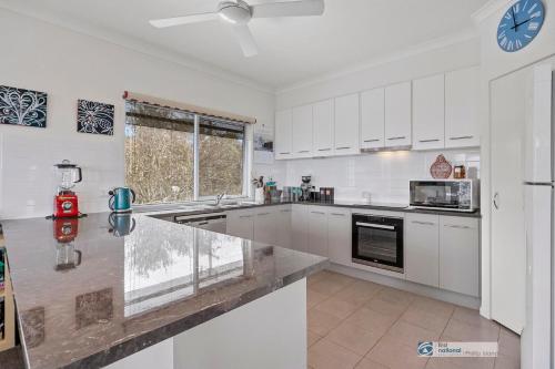 a kitchen with white cabinets and a clock on the wall at Smiths Beach Walk in Smiths Beach