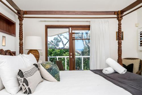 1 dormitorio con 1 cama con sábanas y almohadas blancas en First Light, en Byron Bay