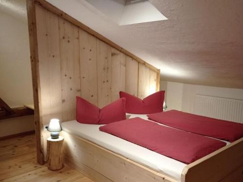 una cama de madera con almohadas rojas en una habitación en Apartment Rossweid, en Stans