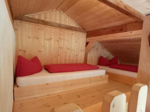 two beds in a wooden cabin with red pillows at Roßweid hut with a fantastic view in Stans