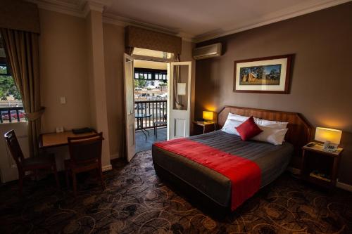 a hotel room with a bed and a desk and a balcony at Quality Hotel Bayswater in Perth