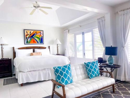 Oceanside Villa @ Ocho Rios, Jamaica Getaway في Boscobel: غرفة نوم بيضاء مع سرير وأريكة