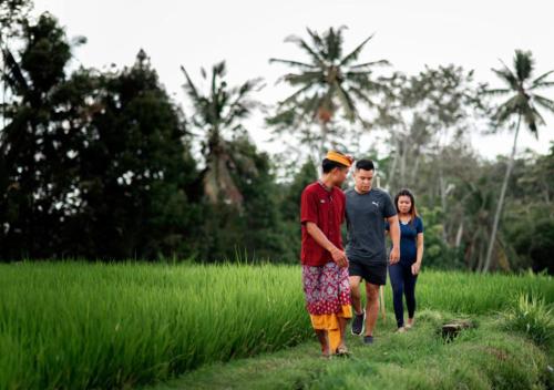 a group of three people walking through a field at Kayangan Villa Ubud in Tegalalang