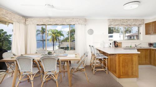 a kitchen with a table and chairs and a large window at Soldiers Point Absolute Waterfront The Peninsula in Soldiers Point