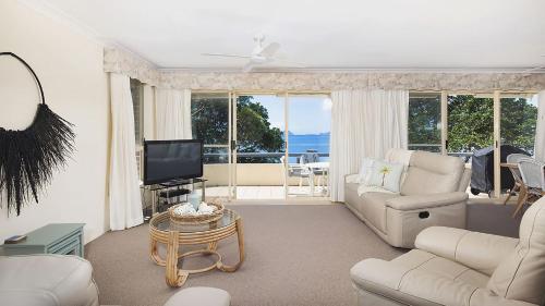 a living room with a couch and a tv at Soldiers Point Absolute Waterfront The Peninsula in Soldiers Point