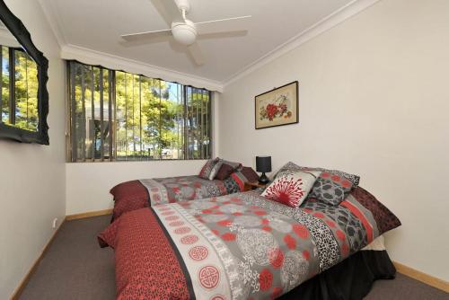 a bedroom with a bed and two windows at Gorgeous Harbourside in Soldiers Point