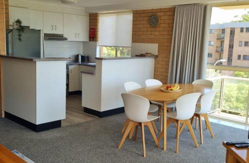 een keuken met een houten tafel en witte stoelen bij Seaspray Walk to the beach in Nelson Bay