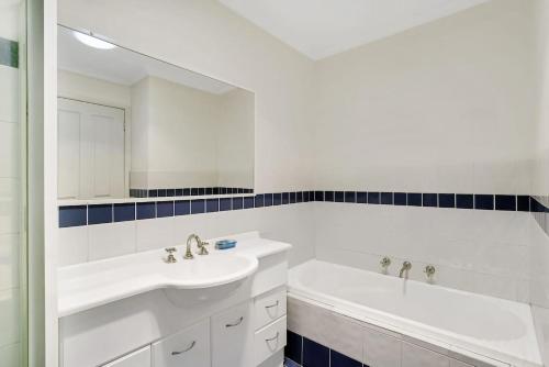 La salle de bains blanche est pourvue d'une baignoire et d'un lavabo. dans l'établissement Townhouse in the heart of Port Stephens, à Salamander Bay