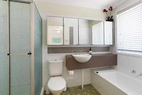 a bathroom with a sink and a toilet and a tub at Views of Wanda Beach in Salamander Bay