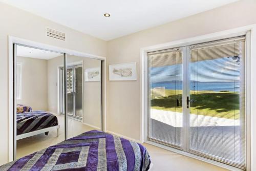 a bedroom with a bed and a large window at Breath Taking Waterfront in Corlette