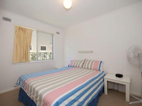 a white bedroom with a bed and a window at Beachside Shoal Bay Unit 4 in Shoal Bay