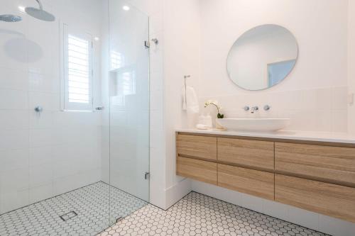 a white bathroom with a sink and a mirror at Biirinba Top Floor - oceanstays in Yamba