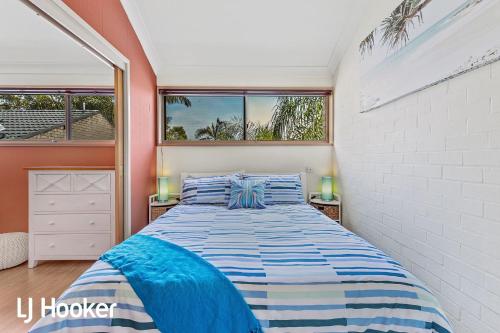 a bedroom with a large bed with blue and white sheets at Amazing waterfront location in Soldiers Point