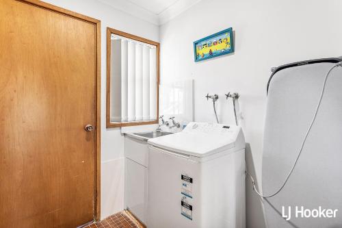 a bathroom with a sink and a washing machine at Cromarty Beach Cottage in the Heart of Anna Bay in Anna Bay