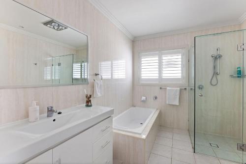 a white bathroom with a sink and a shower at Birubi Beach Waterfront in Anna Bay