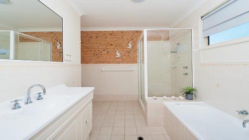 een witte badkamer met een douche, een bad en een wastafel bij Bombora Walking Distance to Fingal Beach in Fingal Bay