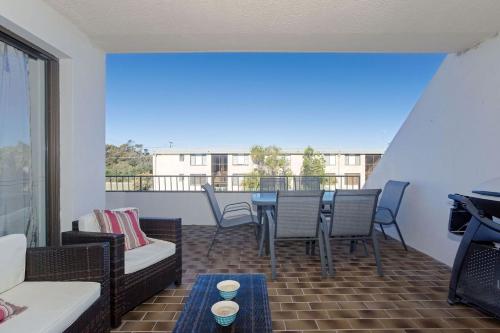 a living room with a table and chairs on a balcony at The Dunes Two bedroom apartment overlooking pool in Fingal Bay