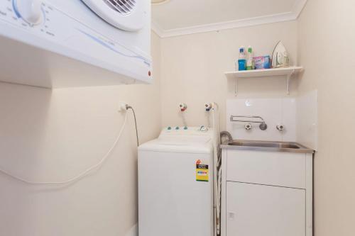a bathroom with a sink and a washing machine at The Dunes Two bedroom apartment overlooking pool in Fingal Bay