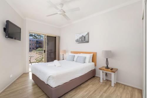 a white bedroom with a bed and a window at Martys Little Beach No 14 in Nelson Bay