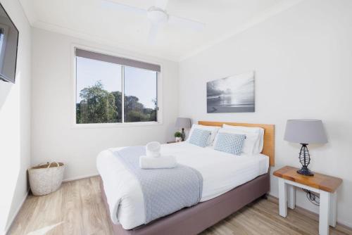 a white bedroom with a bed and a window at Marty s Little Beach No 9 in Nelson Bay