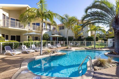 a swimming pool with palm trees and a building at Marty s Little Beach No 9 in Nelson Bay