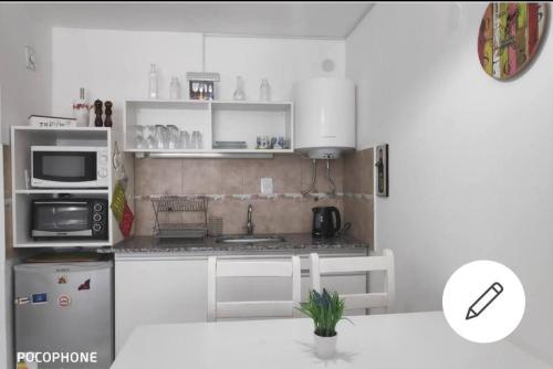 Il comprend une cuisine blanche équipée d'un four micro-ondes et d'un réfrigérateur. dans l'établissement Cómo en casa Monoambiente, à Córdoba