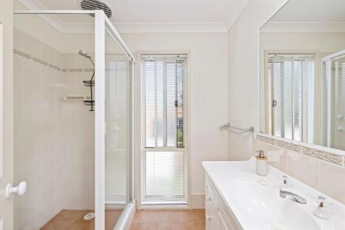 Baño blanco con lavabo y espejo en pet friendly - Views- Meters to the Beach & Anchorage Port Stephens, en Corlette