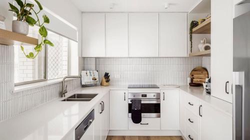 a white kitchen with white cabinets and a sink at Luxury Escape Sundeck Shoal Bay in Shoal Bay